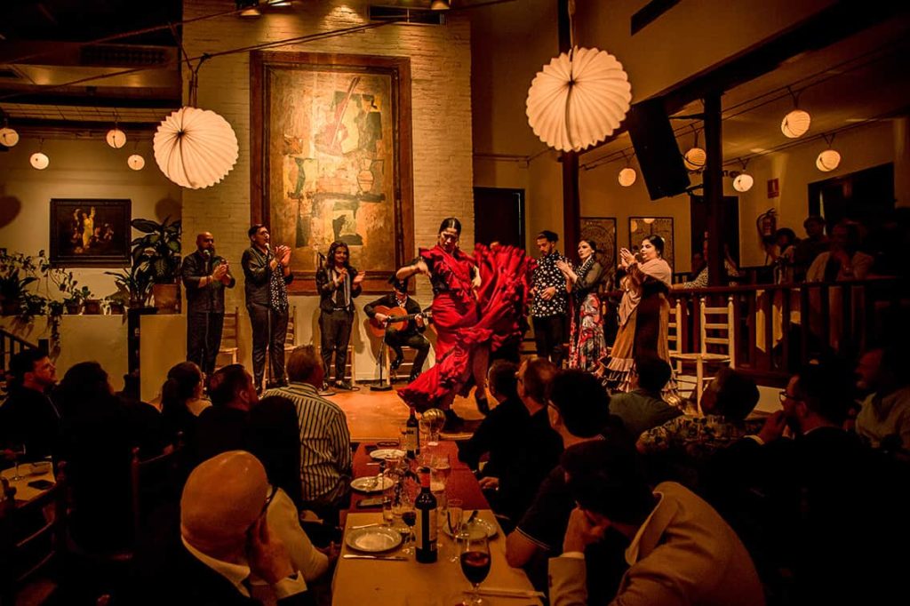 Ensemble d'artistes, chanteurs et guitaristes accompagnant une danseuse en robe rouge pour un flamenco show barcelona.