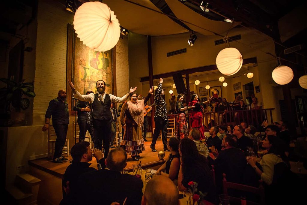 Troupe d'artistes saluant le public à la fin d'un flamenco show barcelona dans une salle chaleureuse.