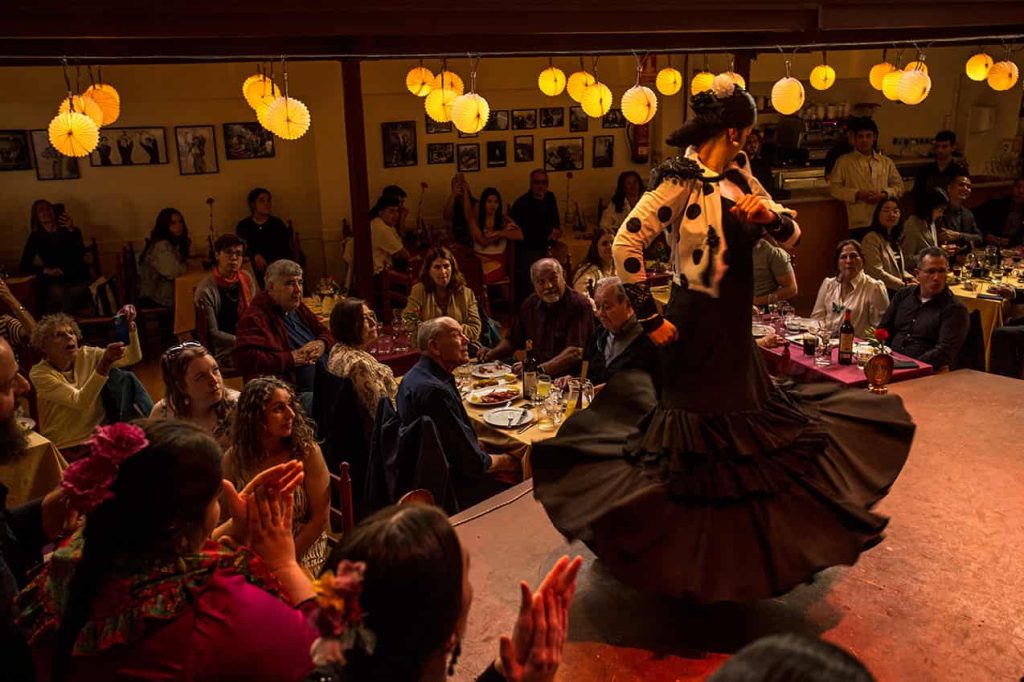 Danseuse en costume traditionnel blanc à pois noirs réalisant une rotation dynamique lors d'un flamenco show barcelona.