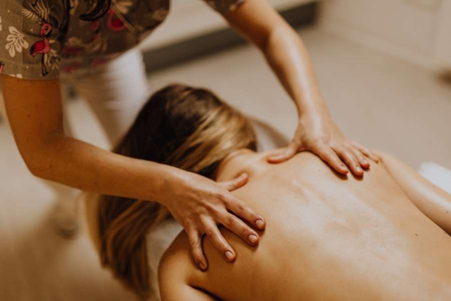 Praticienne massant le haut du dos d'une cliente pour programmer un massage relaxant.